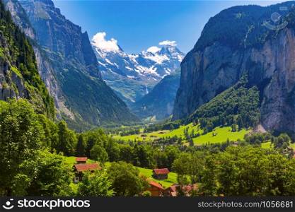 Lauterbrunnen valley, waterfall and the Lauterbrunnen Wall in Swiss Alps, Switzerland. Eiger, Monch and Jungfrau mountains in the background.. Mountain village Lauterbrunnen, Switzerland
