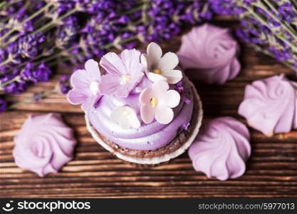 Lavender cakes - cupcake and lilac meringue on a wooden table. Lavender cakes