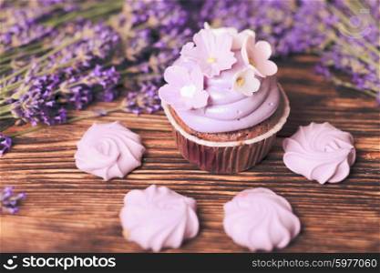 Lavender cakes - cupcake and lilac meringue on a wooden table. The Lavender cakes