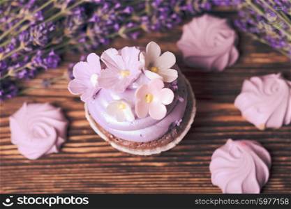 Lavender cakes - cupcake and lilac meringue on a wooden table. The Lavender cakes