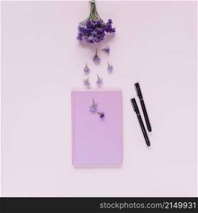 lavender closed notebook two felt tip pens pink background