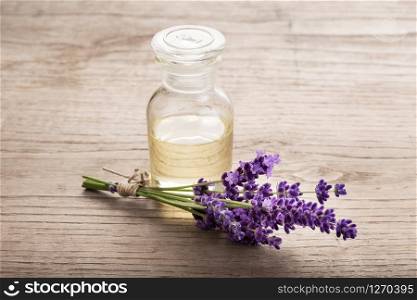 Lavender essential oil in glass bottle on wooden table. Copy space