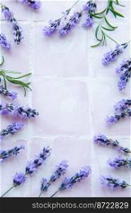 Lavender flowers and leaves creative frame on a pink tile background. Top view, flat lay. Floral composition