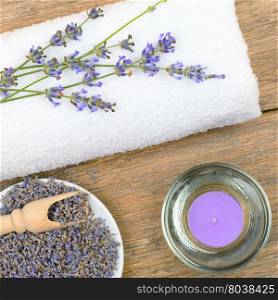 lavender flowers, aromatic candles, and towels on wooden background