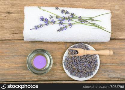 lavender flowers, aromatic candles, and towels on wooden background