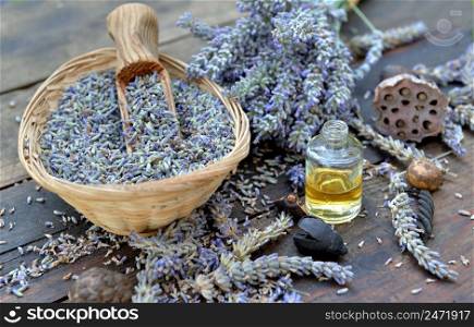 lavender flowers petals from garden  in a little basket with essential oil bottle on a wooden table 