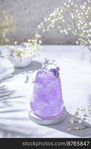 Lavender Gin and Tonic Punch Cocktail. Elegant glass filled with violet cocktail or mocktails surrounded by ingredients, lavender and white gypsophila flowers on light gray table surface. Ready for drinking.