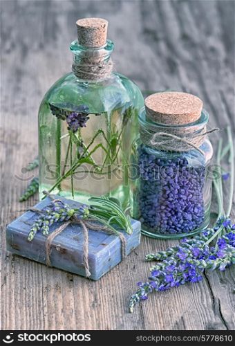 lavender oil, herbal soap and bath salt with fresh flowers on wooden background. vintage style toned picture