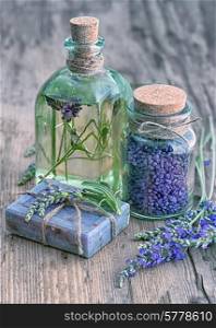 lavender oil, herbal soap and bath salt with fresh flowers on wooden background. vintage style toned picture