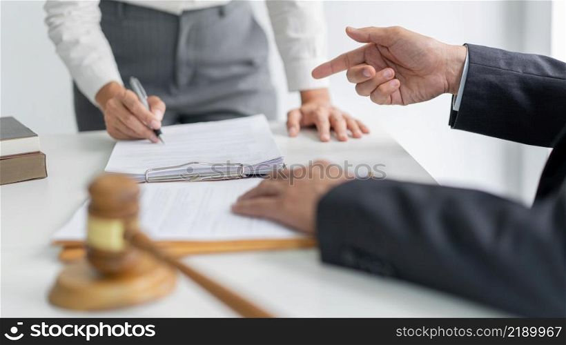 law concept The barrister helper standing, holding a pen in his hand, and reading the term that seems to be confused for him to his boss.