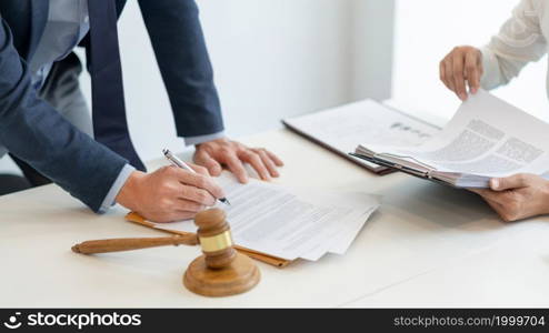 law concept the lawyer in blue suit standing and verifying the official paper carefully by rechecking with his assistant.