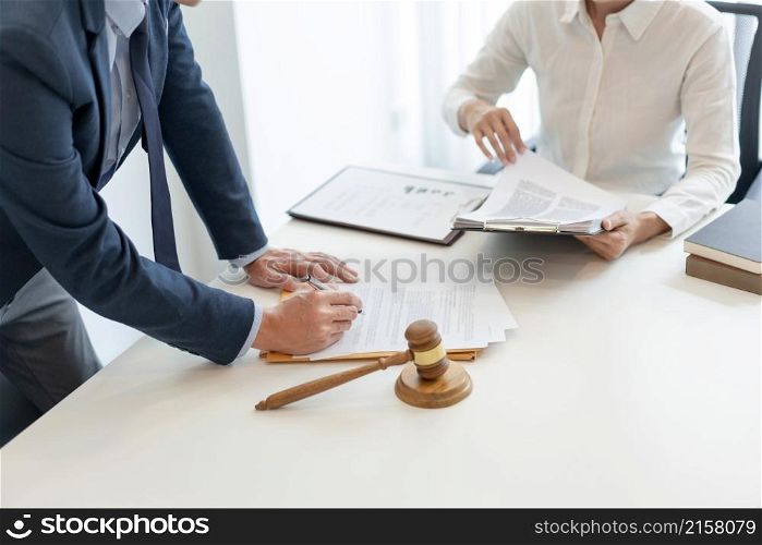 law concept the lawyer in blue suit standing and verifying the official paper carefully by rechecking with his assistant.