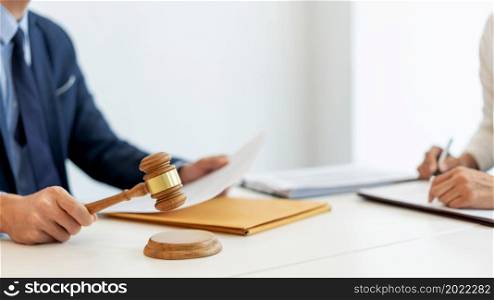 law concept the legal representative in deep blue suit gavel to approve agreement in the official document that the company submits to him while his aider sitting at the same desk with him.