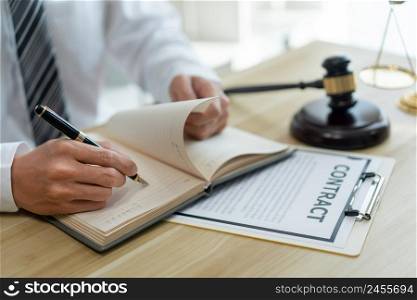 Law consultancy concept A male prosecutor reviewing his sentences of contract on his own notebook before writing them down on the contract paper