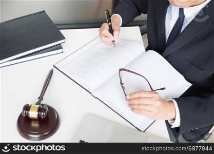 lawyer hand writes the document in court (justice, law) with sounding block.