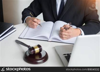 lawyer hand writes the document in court (justice, law) with sounding block.