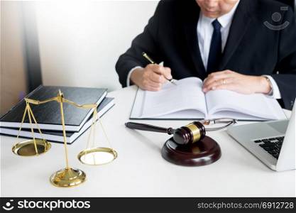 lawyer hand writes the document in court (justice, law) with sounding block and golden Weight.