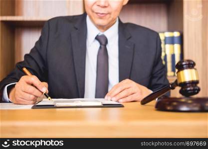 lawyer judge reading documents at desk in courtroom working on wooden desk background. gavel golden Weight. and soundblock of justice