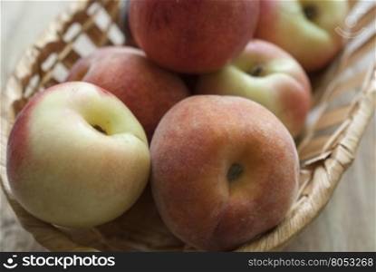 lay the peaches in a wicker basket. Peaches are in the basket on weathered wooden surface