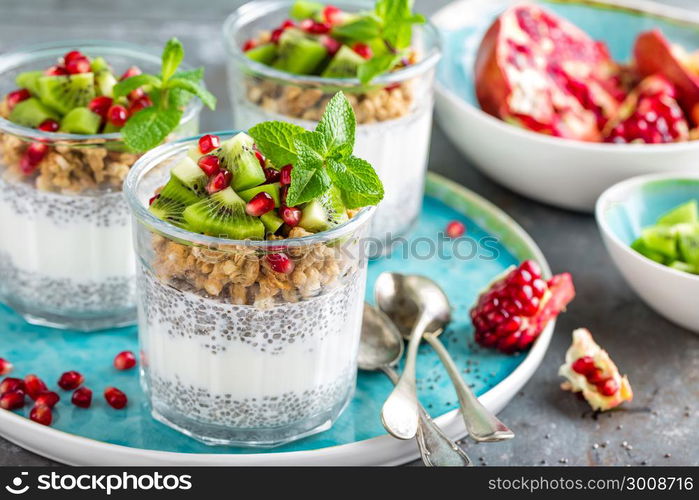 Layered chia pudding parfait with kiwi fruit, pomegranate, granola and yogurt, healthy breakfast