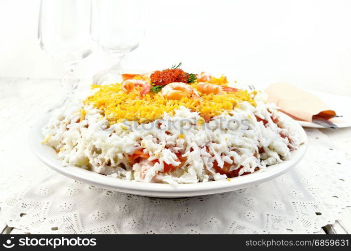 Layered salad of salmon, squid, shrimp, avocado, rice and eggs in a plate, napkin on the background light wooden boards