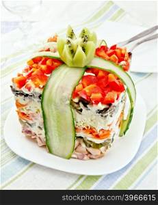Layered salad with chicken, egg, mushrooms and cucumber, carrots and pepper, mayonnaise on the plate against the background of napkin