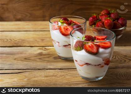 Layered strawberry dessert on wooden background. Layered strawberry dessert on wooden background. Diet yogurt dessert with ripe strawberry.
