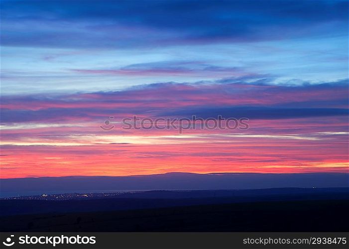 Layers of color at sunset over town lights during Winter