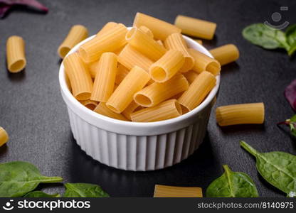 Layout of Italian raw pasta, top view, different types and shapes of pasta. Detail of macaroni pasta useful as a background, texture. Dry pasta. Top view on black background