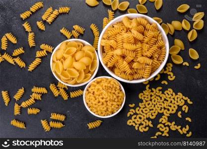 Layout of Italian raw pasta, top view, different types and shapes of pasta. Detail of macaroni pasta useful as a background, texture. Dry pasta. Top view on black background