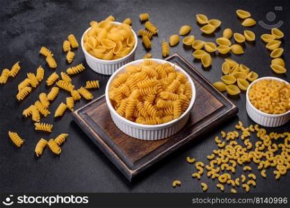 Layout of Italian raw pasta, top view, different types and shapes of pasta. Detail of macaroni pasta useful as a background, texture. Dry pasta. Top view on black background