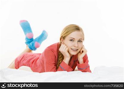 Laziness relax concept. Smiling positive teen girl in bed. Lazy youthful female wearing red dotted pajamas blue cozy socks lying on pillow in good mood.. Smiling woman lying in bed