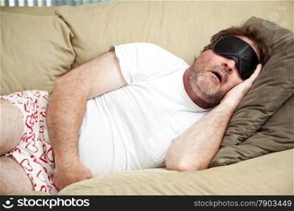 Lazy man at home in his underwear, sleeping on the couch and snoring.