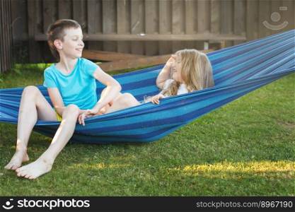 χldren brother and sister play in the garden on a hammock..χldren brother and sister resting in the garden on a hammock