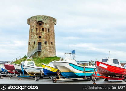 Le Hocq British round coastal defence tower with colorful boats in the foreground, bailiwick of Jersey, Channel Islands