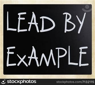 ""Lead by example" handwritten with white chalk on a blackboard"