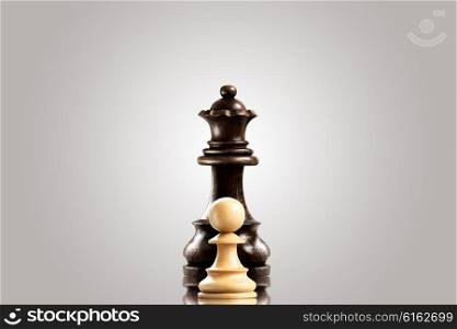 Leadership and bravery concept; white wooden single pawn staying against a black queen.