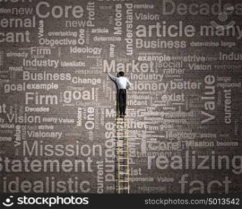Leadership concept. Rear view of businessman standing on ladder and writing business concepts on wall