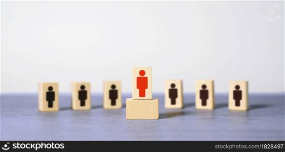 Leadership in business or team manager concept with a red abstract leader icon printed on a wooden block leading among the others with copy space on defocused background.