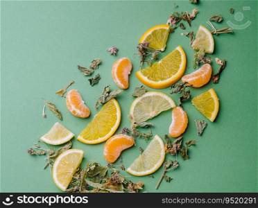 Leaf tea with orange and tangerine slices on green background