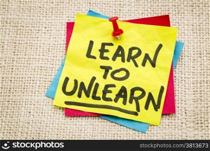 learn to unlearn - advice or motivation words on a sticky note against burlap canvas