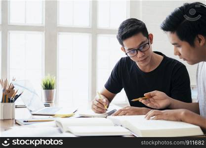 Learning, education and school concept. Young men studying for a test or an exam. Tutor books with friends. Young students campus helps friend catching up and learning.