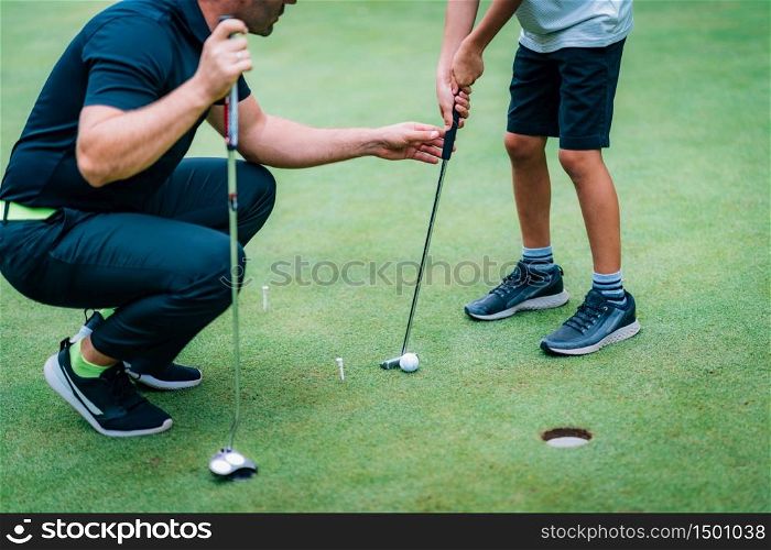 Learning Golf. Boy practicing putting with instructor