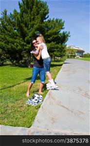 Learning mother and daughter on roller skates in summer