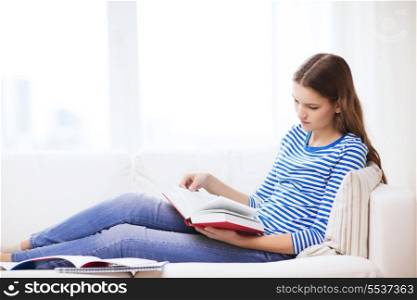 leasure and home concept - calm teenage girl woman reading book and sitting on couch at home