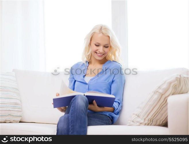 leasure and home concept - smiling middle-aged woman reading book and sitting on couch at home