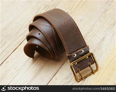 leather belt with a buckle on a wooden board