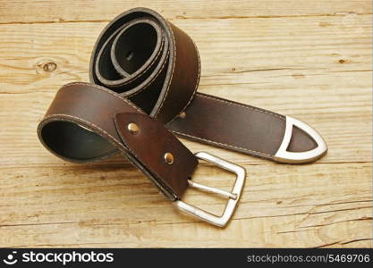 leather belt with a buckle on a wooden board