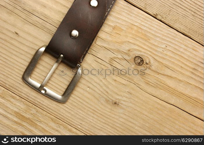 leather belt with a buckle on a wooden board