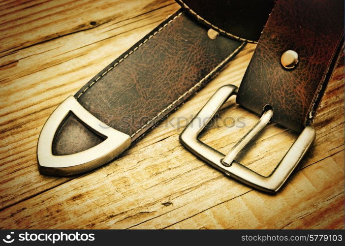 leather belt with a buckle on a wooden board. Toned